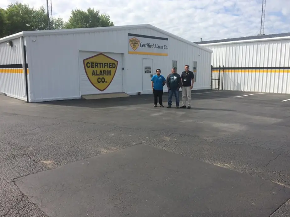 Three of the Certified Alarm team outside the Sheffield shop, shield on the garage door