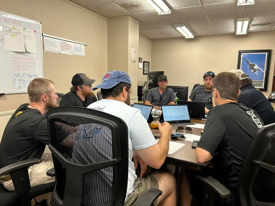 Certified Alarm technicians around a table with laptops at the Sheffield office